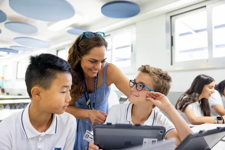 Teacher smiling with two students in the classroom 